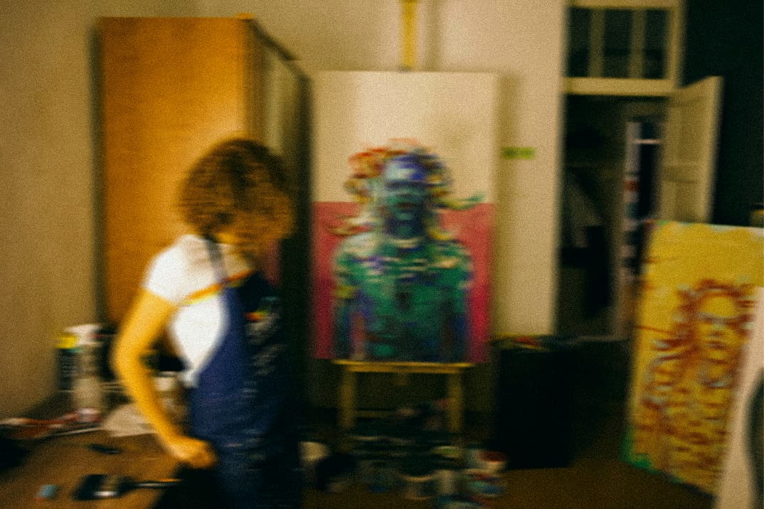 A painter moving past a portrait on an easel in her studio, blurred mid-step.
