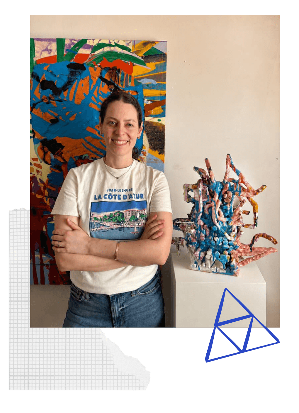 Katie Kirk in her studio, standing between one of her paintings and a glazed ceramic sculpture.