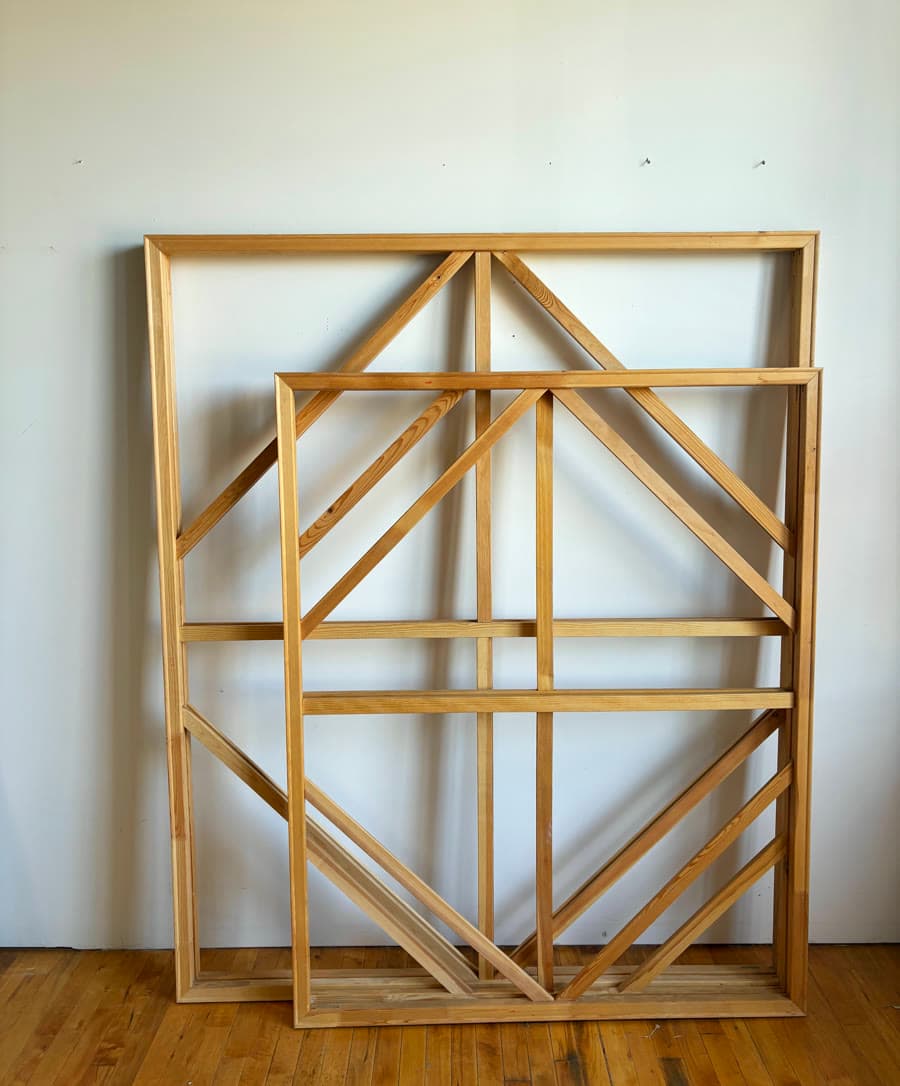Two nested wooden stretcher frames leaning against a studio wall.